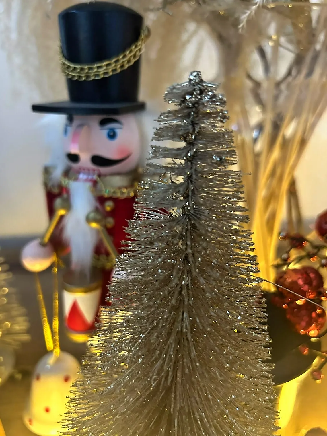 Gold glitter bottle-brush tree with a nutcracker drummer behind it